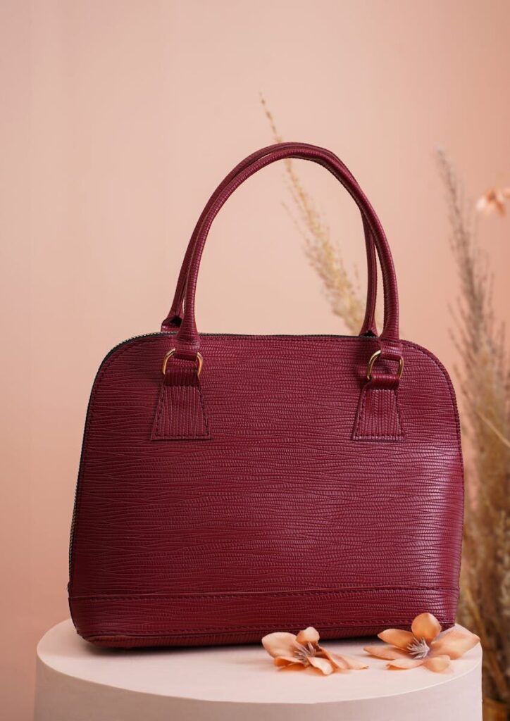 Luxurious red handbag elegantly displayed against pastel backdrop with floral accents.